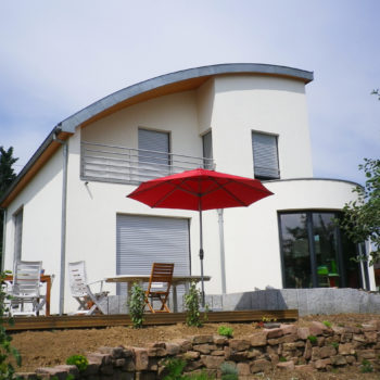 Maison individuelle ossature et charpente bois, toit et murs courbés, revêtement crépis